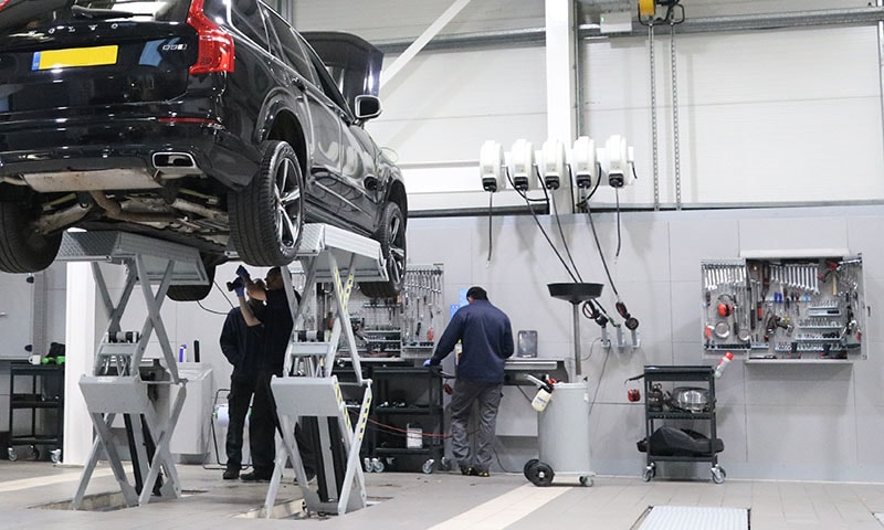 Mechanics servicing a car on a workshop lift