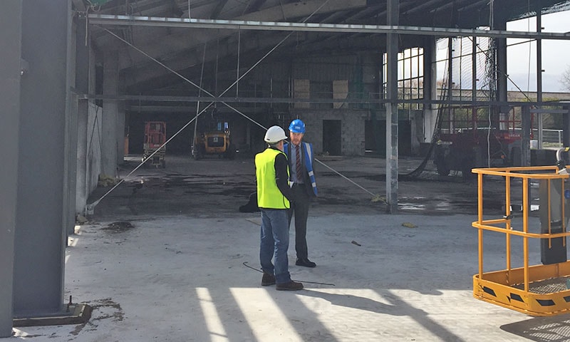 Engineer conducting a site survey with floor plan and measuring equipment