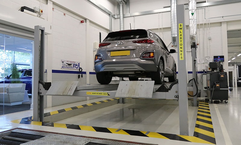 Four-post vehicle lift in an MOT inspection bay